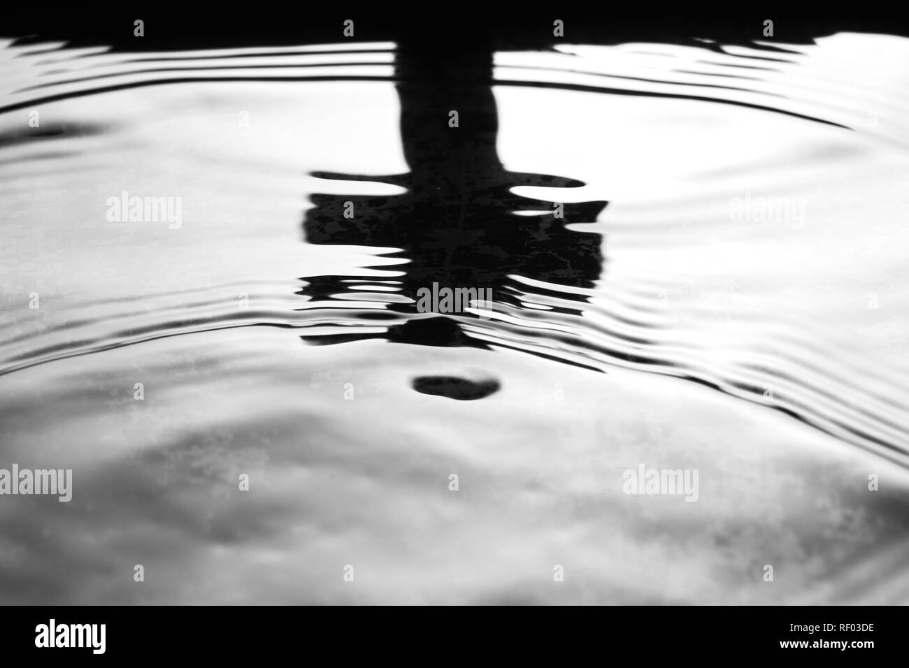 Bianco e nero concetto religioso con la croce che riflette in acqua Foto Stock