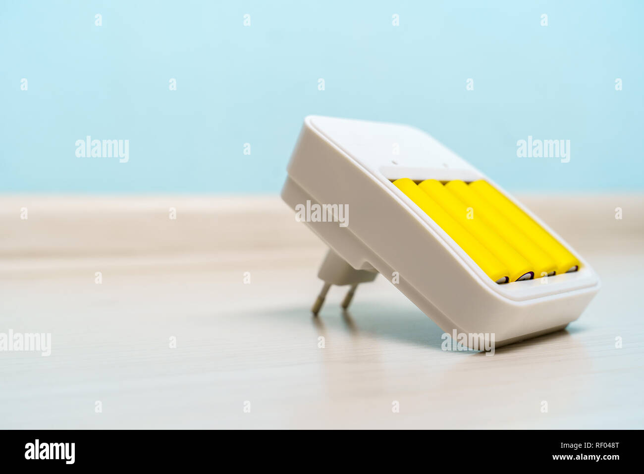 Immagine di un caricabatterie con due batterie giallo vuota su sfondo blu Foto Stock