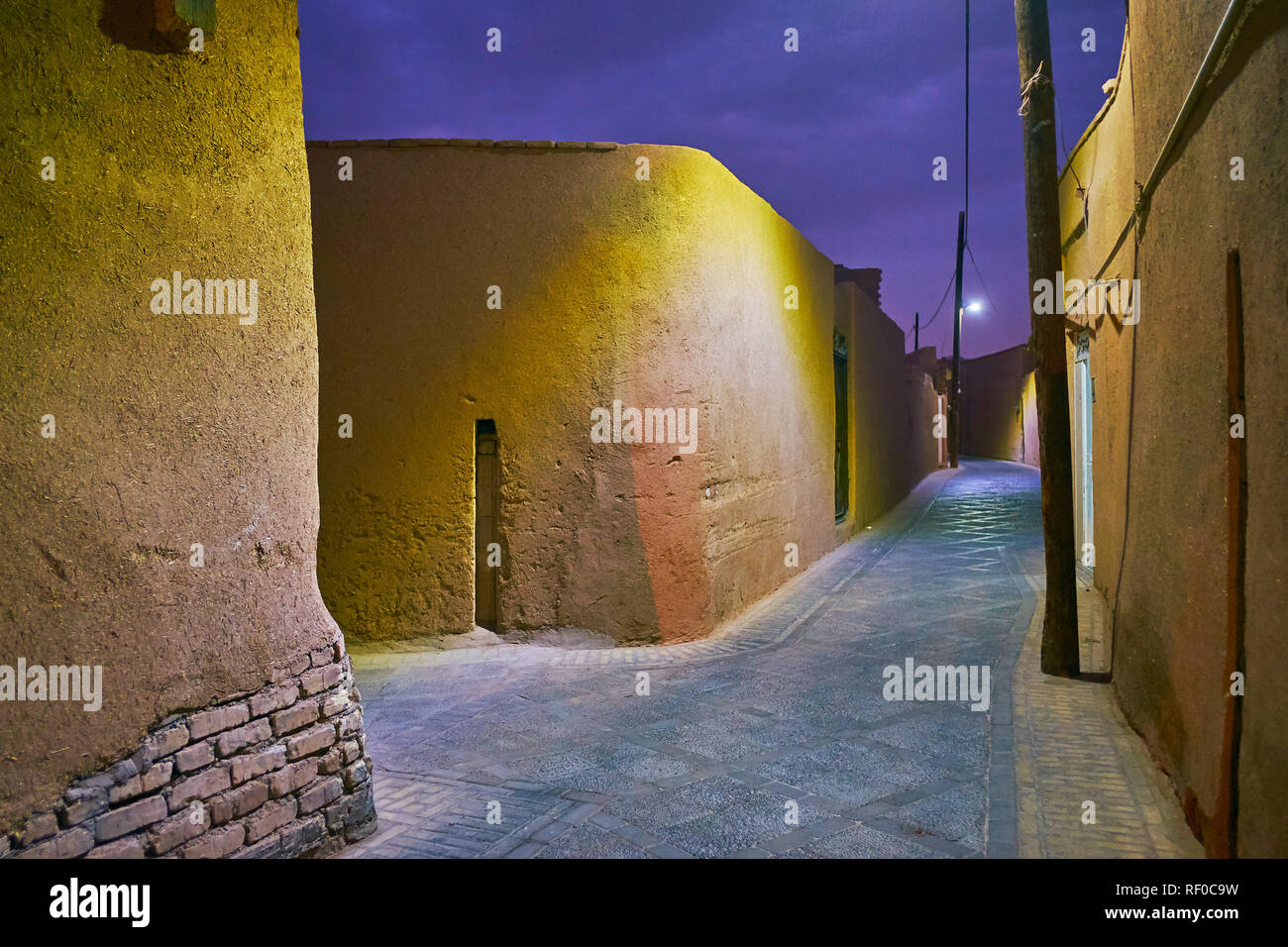 A piedi la strada tranquilla di Yazd quartiere medievale con conserva di adobe buldings e muro alto-recinzioni, Iran. Foto Stock