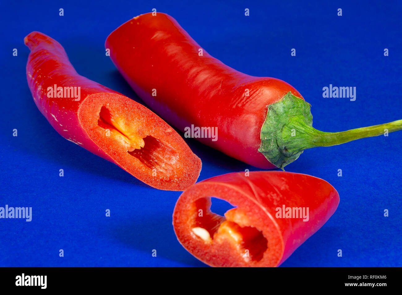 Chiudere uno fresco affettato peperoncino rosso su sfondo blu, basso angolo vista laterale Foto Stock
