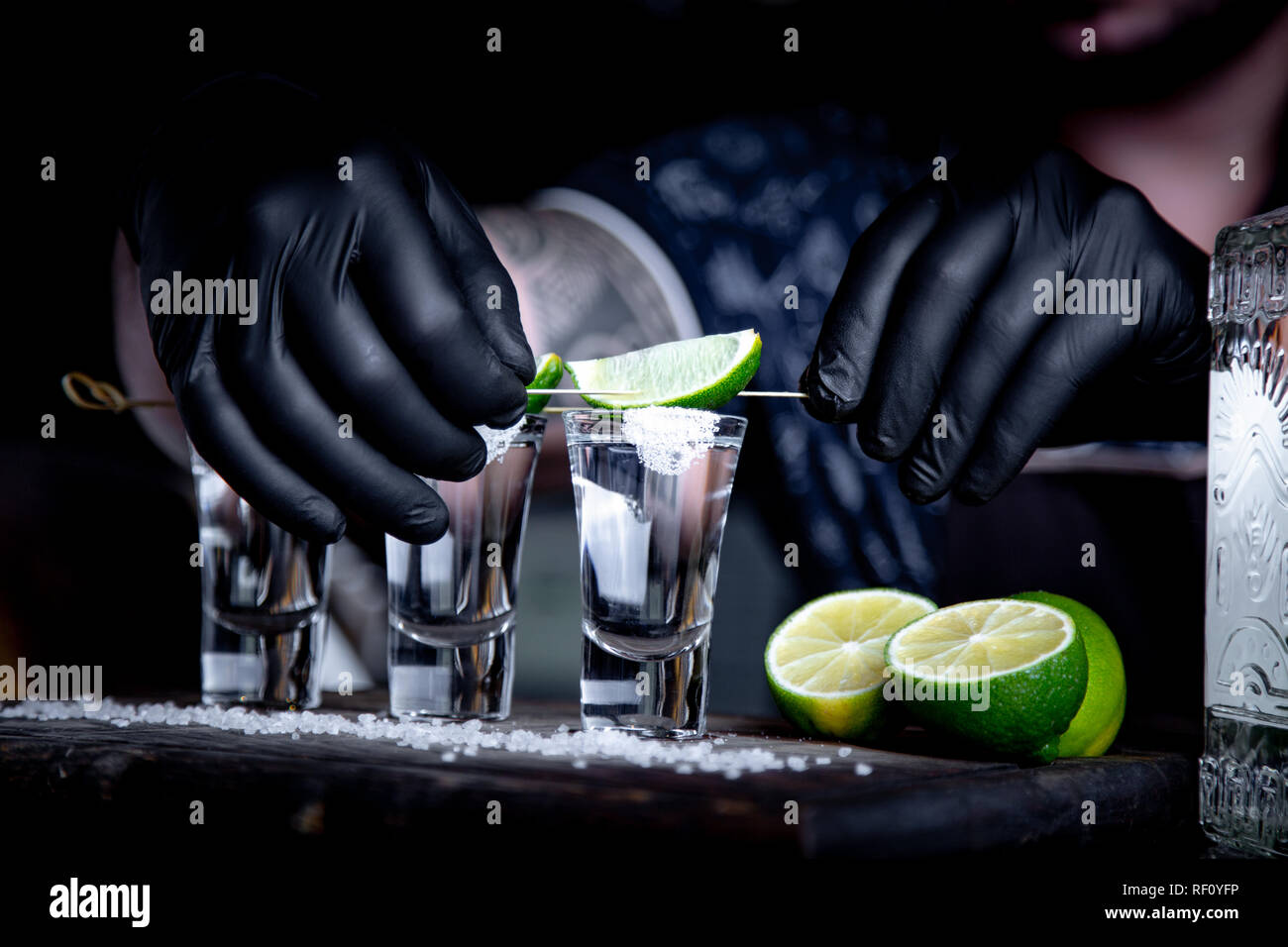 Aperitivo con gli amici nel bar, tre bicchieri di alcool con calce e sale per la decorazione. Scatti di tequila, il fuoco selettivo Foto Stock