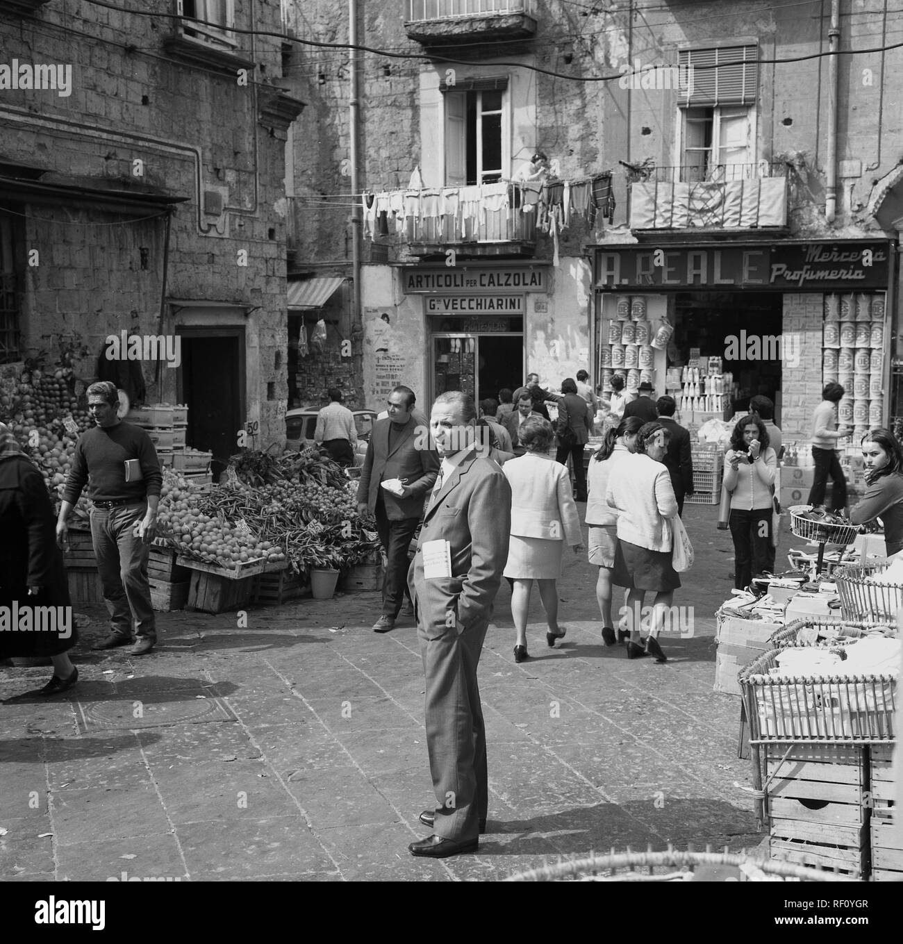 Anni sessanta, Italia, Napoli, outdoor street market, locali italiani passeggiare tra le bancarelle di frutta e verdura e piccoli oggetti di uso domestico. Foto Stock