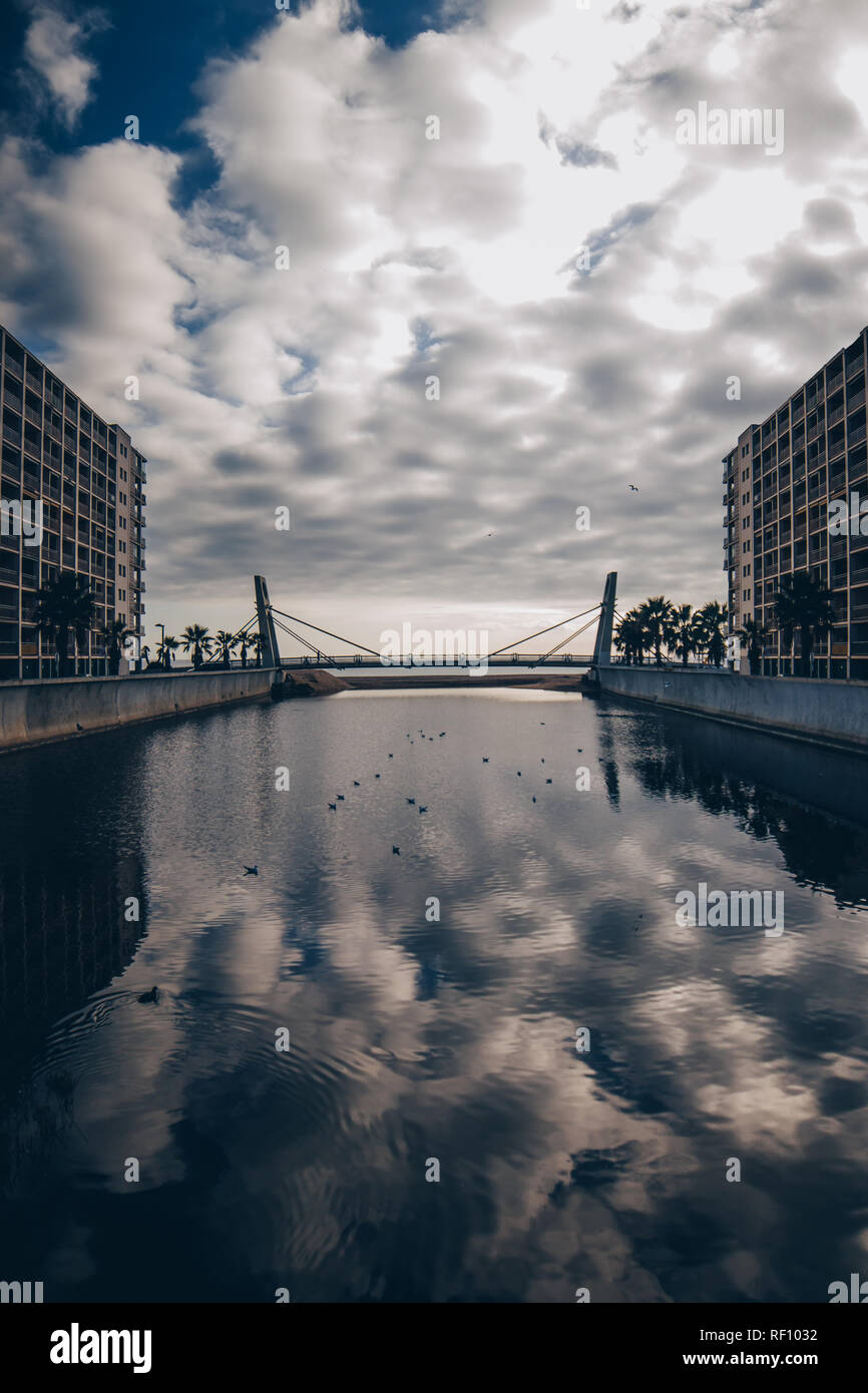 Concetto di superficie di acqua tra gli edifici moderni e cielo nuvoloso Foto Stock