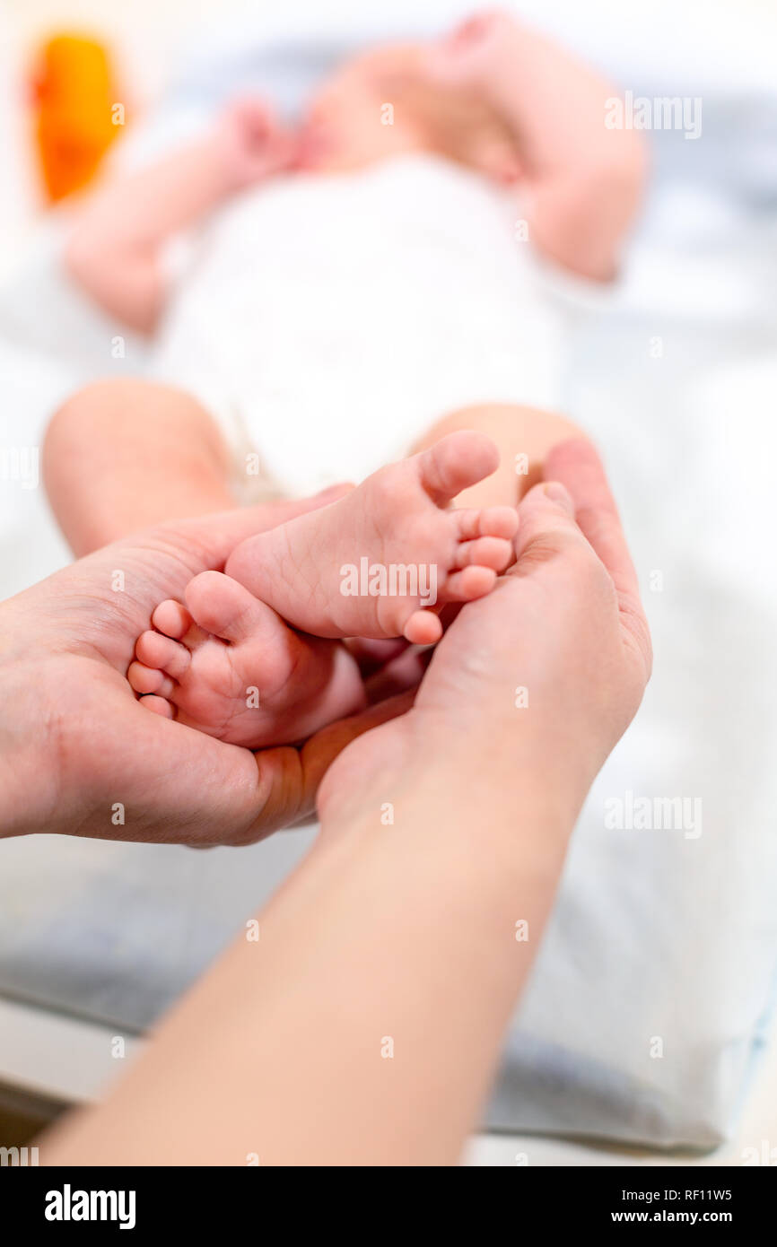 Piedi del bambino nelle mani di madre. Piccolo Neonato con i piedi sul  sagomato femmina closeup