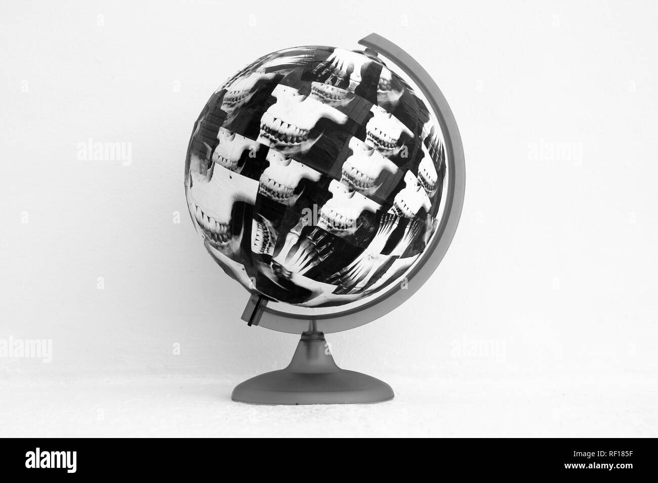 Globo coperta con la carta umana struttura scheletrica di viso e piedi. Le immagini che mostrano le ossa umane incollato con colla su un globo del nostro mondo che intendono illustrare il potenziale distruzione della nostra esistenza per quanto riguarda il cambiamento climatico. Concetto realizzata dal fotografo. Immagine potrebbe essere utilizzato come parte di una copertina di un libro. Il riscaldamento globale. Estinzione. Estinti. La razza umana. Piede di carbonio stampa. Inquinamento di plastica. Foto Stock