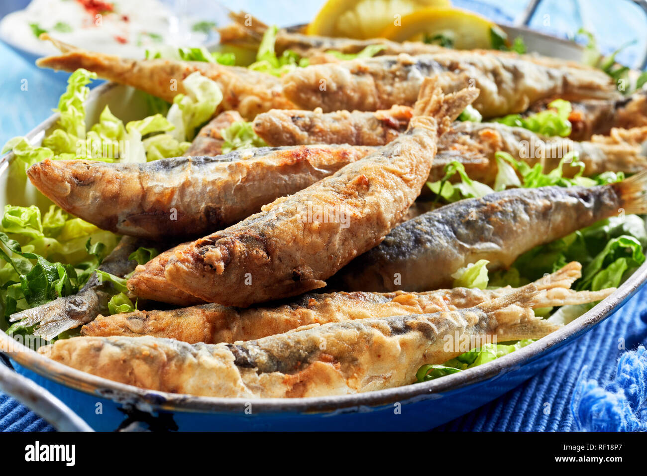 Greco tradizionale croccante le sardine fritte in pastella su un letto di fresco verde lattuga in una vista ravvicinata Foto Stock