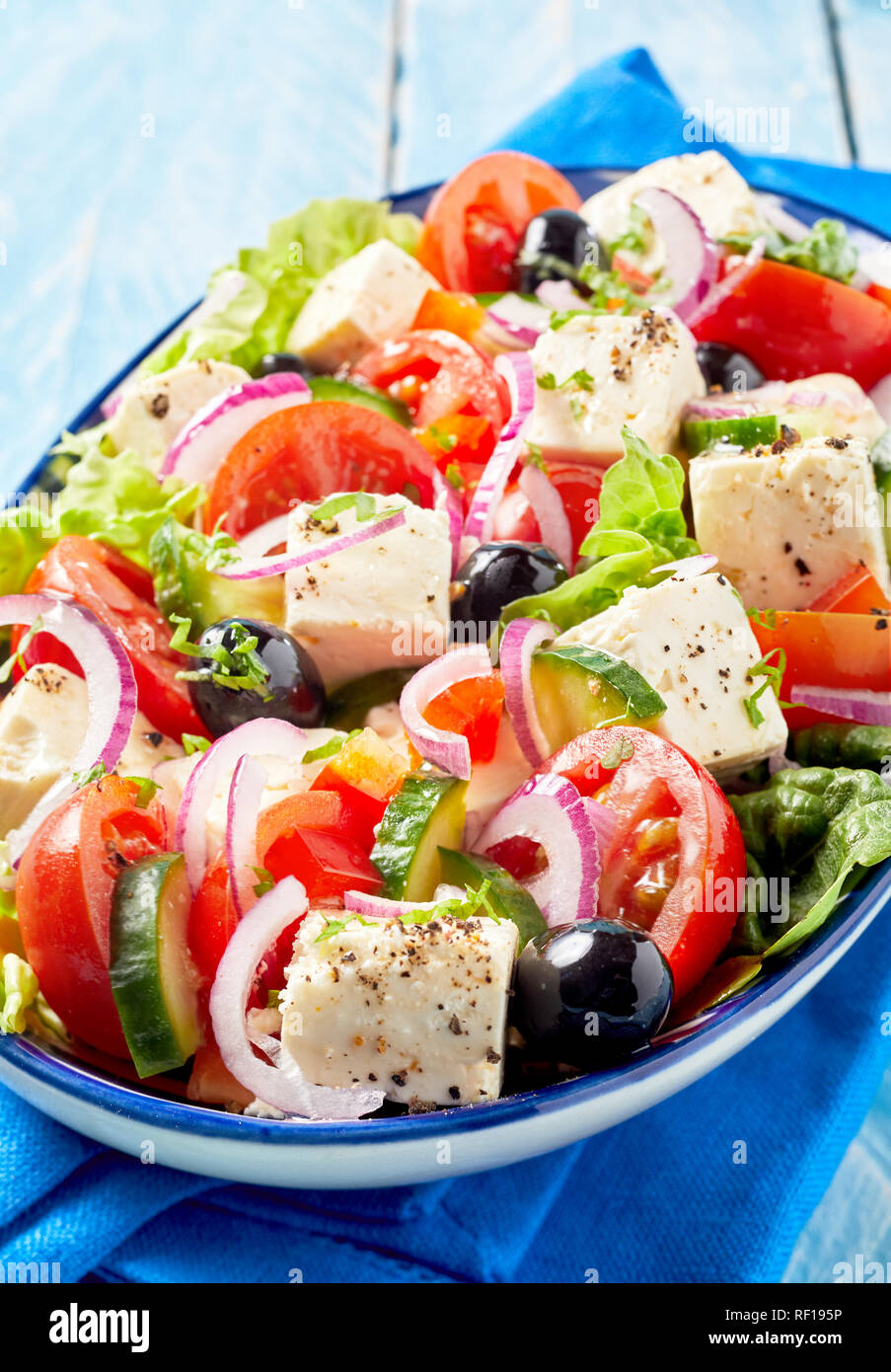 Deliziosa insalata greca con il formaggio feta, le olive, lattuga,il cetriolo, la cipolla e pomodoro servite su un piatto di forma ovale in una vista ravvicinata di un menu e adverti Foto Stock