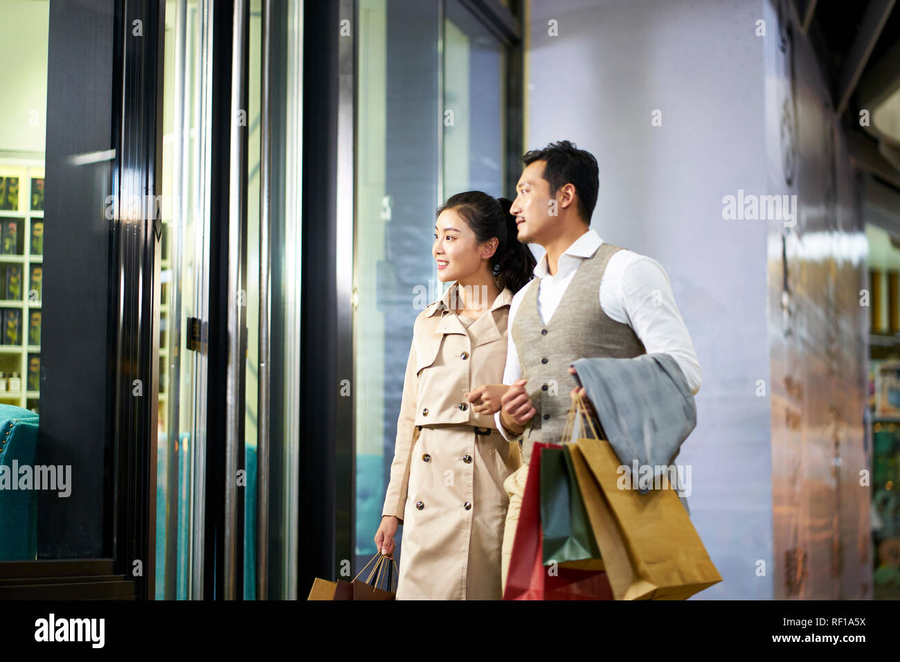 Felice giovani asiatici giovane guardando nella vetrina di un negozio nel centro commerciale per lo shopping Foto Stock