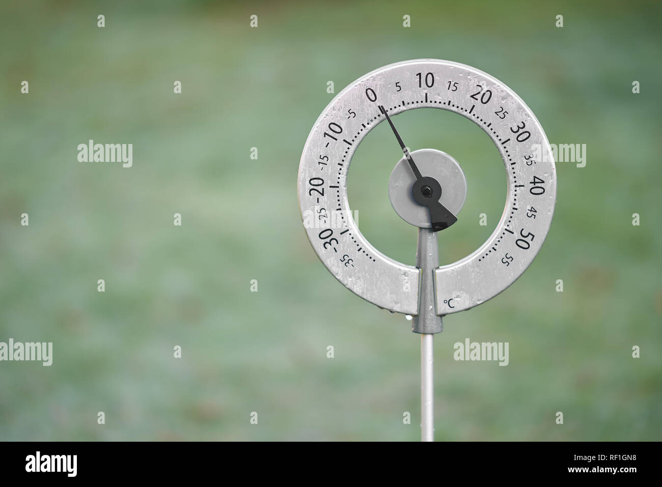 Giardino circolare termometro che mostra una temperatura di zero gradi centigradi con il ghiaccio su di essa lo scongelamento. Foto Stock