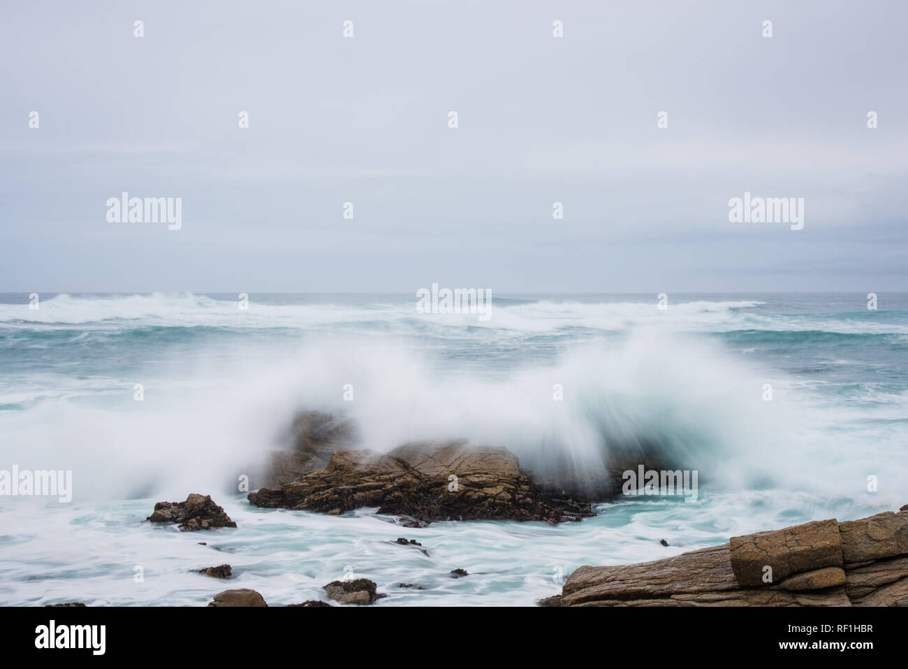 Onde infrangersi contro una costa rocciosa nel morbido mattina lifht. Foto Stock