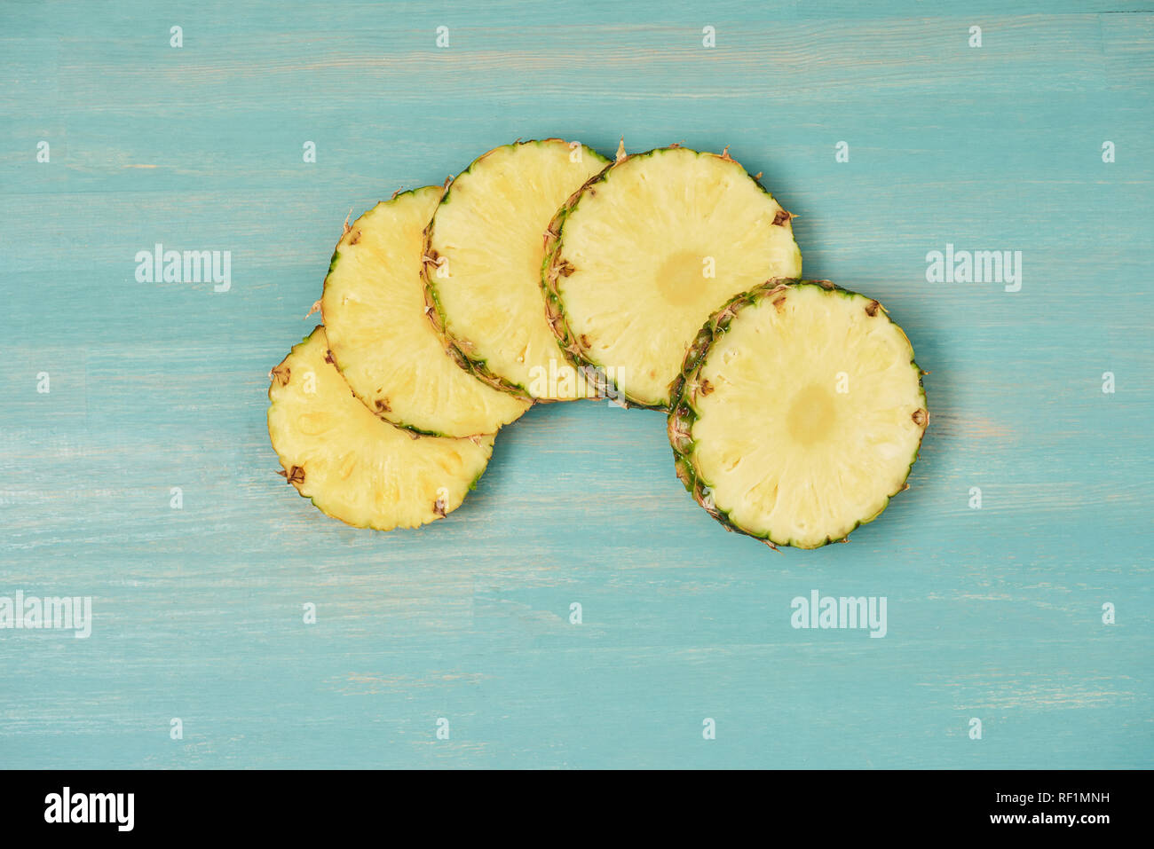 Vista dall'alto di ananas a fette cerchi sul turchese tavolo in legno Foto Stock