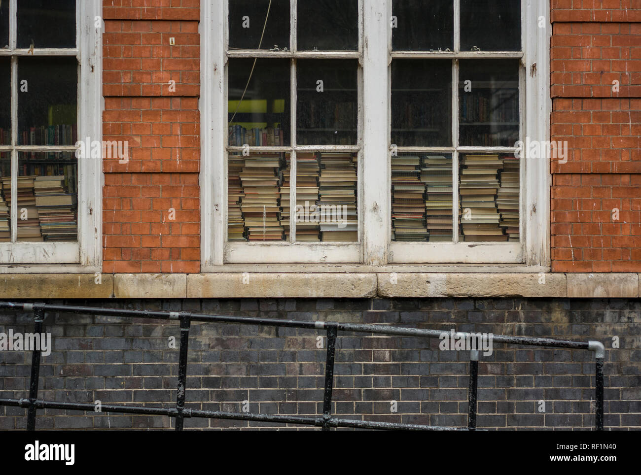 Libri impilati nella finestra dell'ex Deal Street scuola elementare all'angolo di Hanbury Street, ora il Montefiore centro comunitario Foto Stock