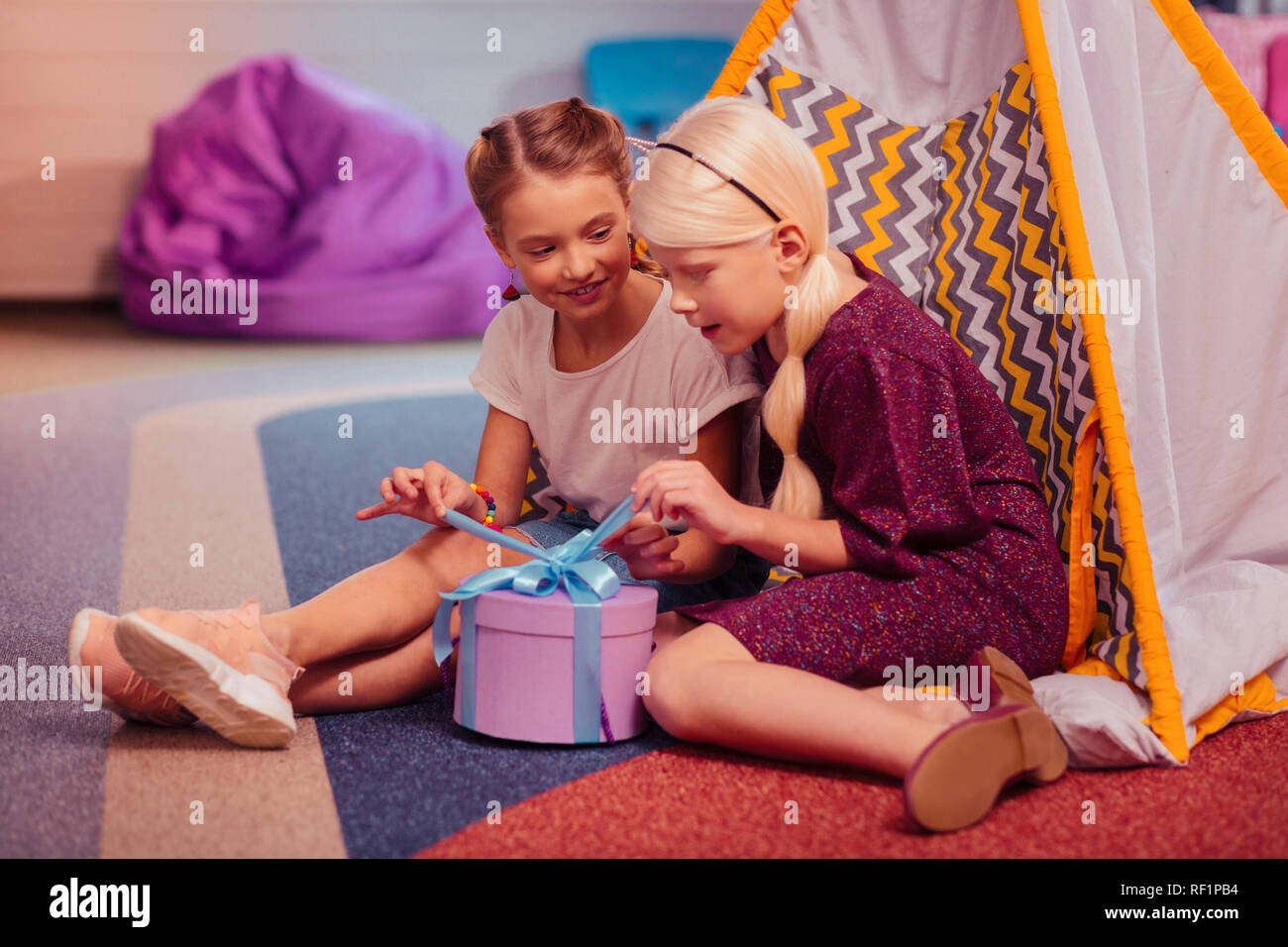 Positive le ragazze felici apertura della casella con il presente Foto Stock
