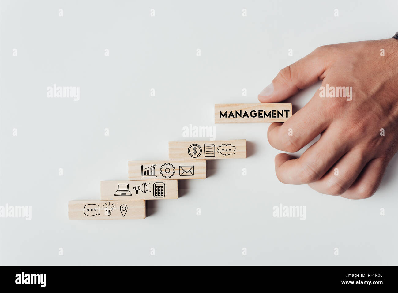 Vista ritagliata dell uomo con il blocco di legno con la parola "di gestione" sulla parte superiore dei mattoni in legno con icone isolato su bianco Foto Stock