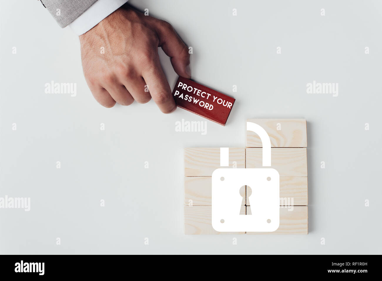 Vista parziale dell'uomo azienda mattone con 'Proteggi la tua password' scritte su blocchi di legno con icona a forma di lucchetto isolato su bianco Foto Stock