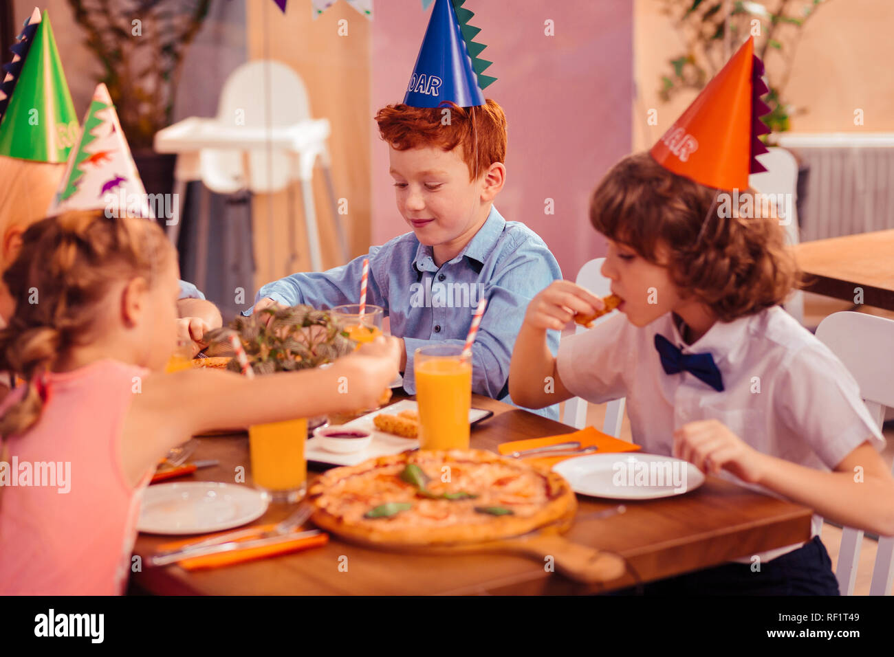 Fame brunette boy mangiare formaggio stick in cafe Foto Stock
