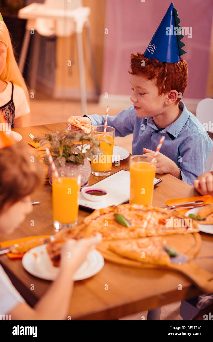 Deliziati dai capelli rossi ragazzo indossa cappello di carta Foto Stock