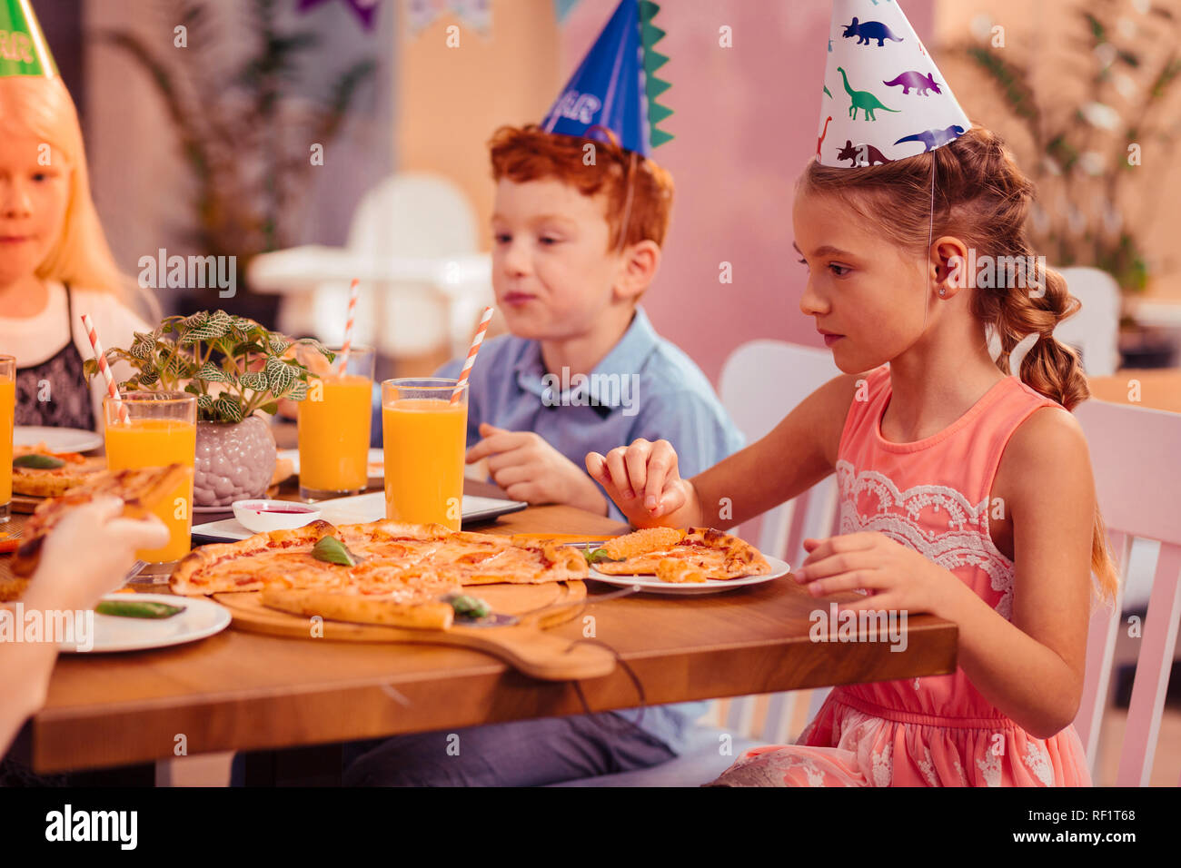 Concentrato ragazza longhaired guardando il bicchiere con succo Foto Stock
