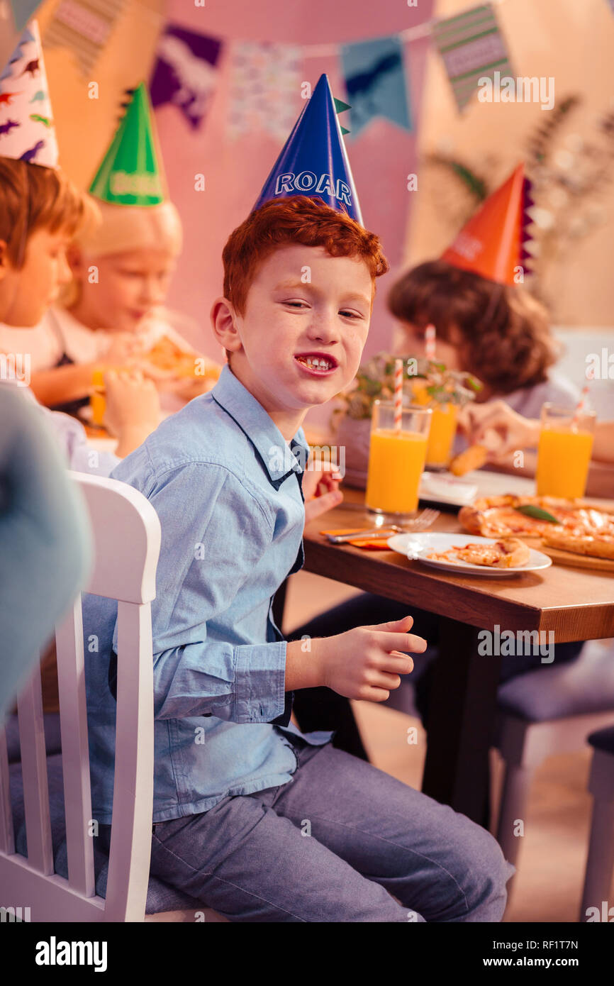 Positivo il piacere ragazzo seduto vicino ai suoi amici Foto Stock