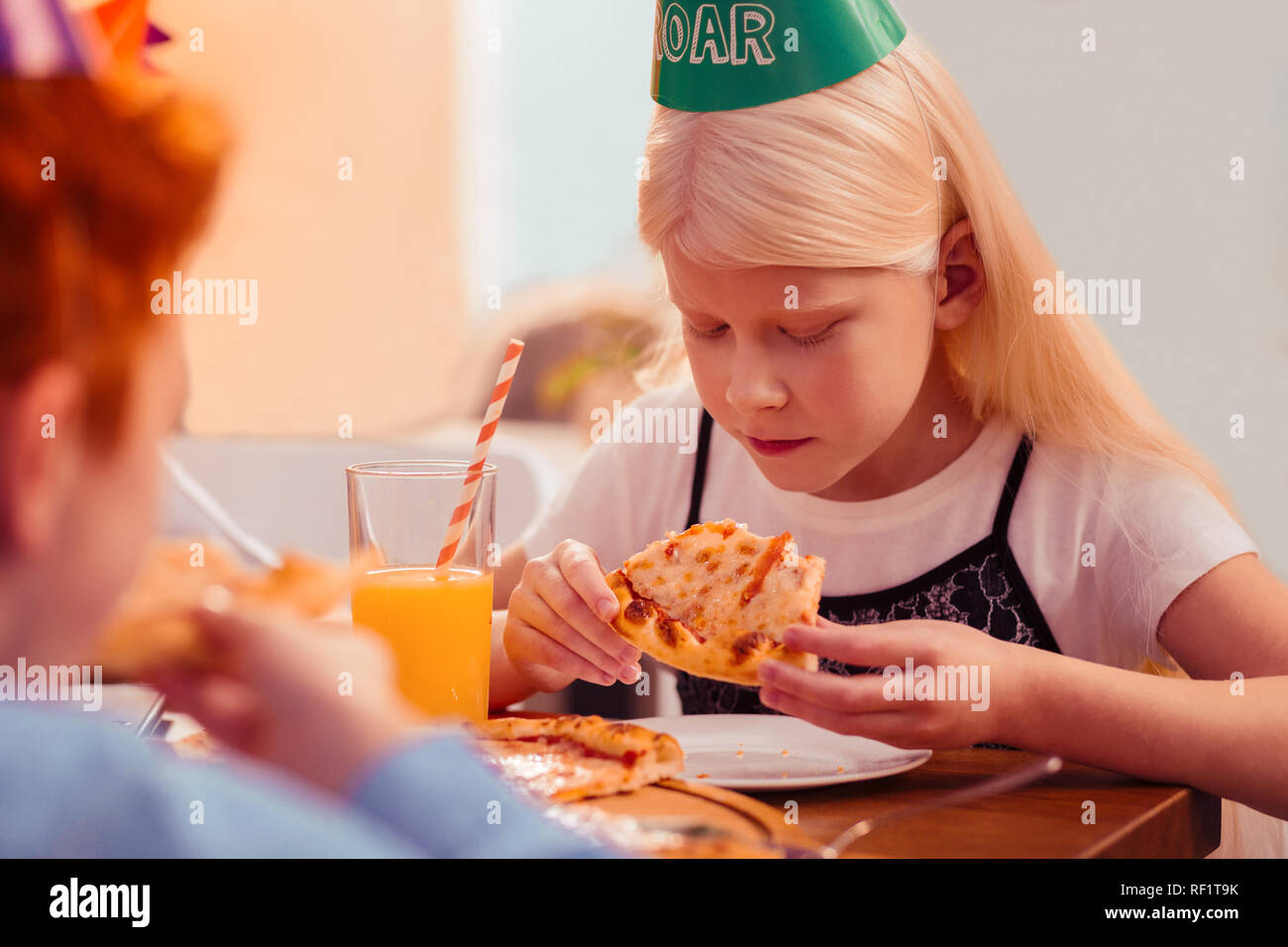 Concentrato longhaired ragazza bionda guardando a pezzi di pizza Foto Stock