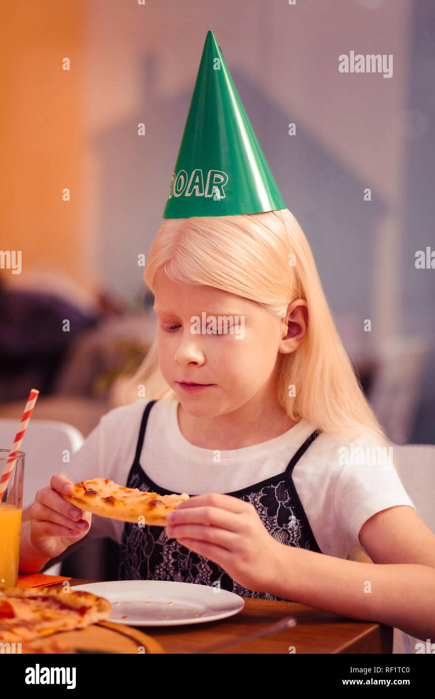 Grave longhaired ragazza bionda fissando la pizza Foto Stock