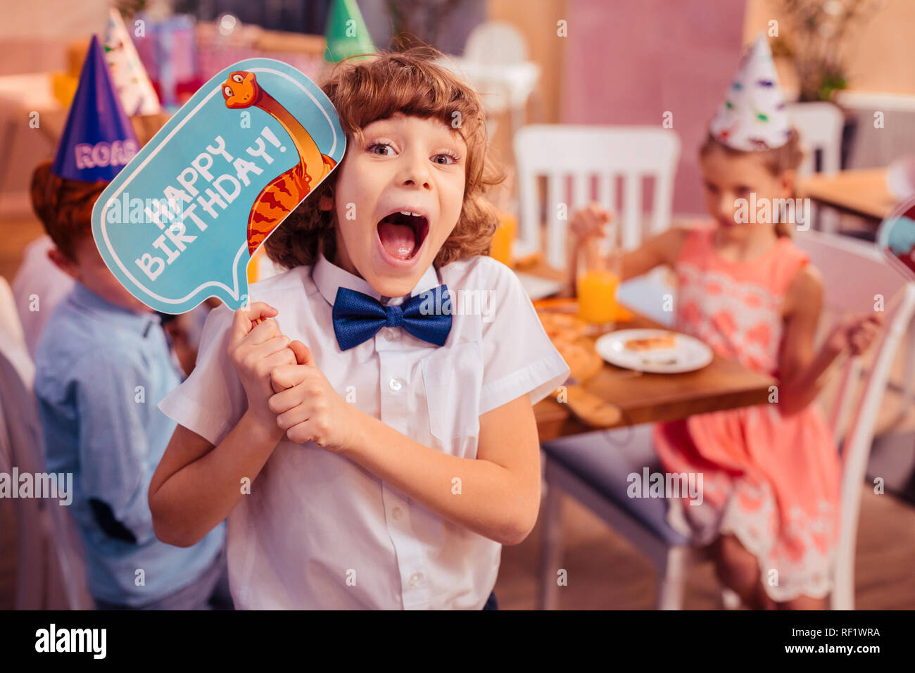 Emotiva dai capelli ricci kid mantenendo la bocca aperta Foto Stock