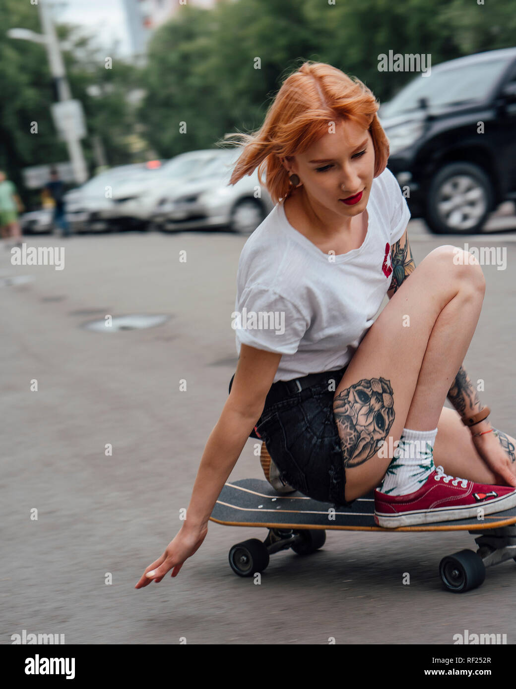 Giovane donna cavallo su carver skateboard su una strada Foto Stock