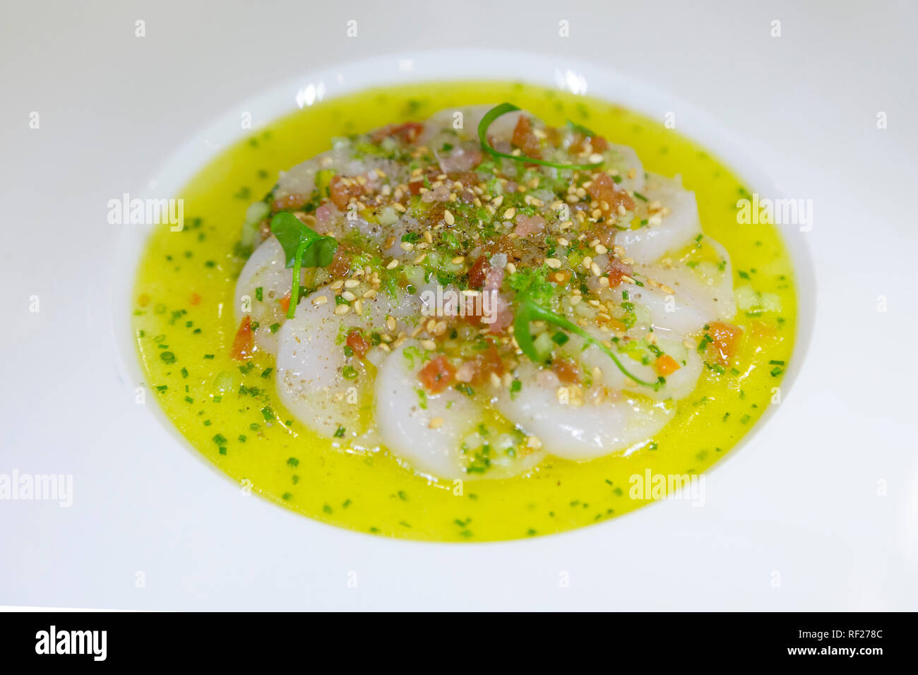Un carpaccio di capesante servito in una salsa piccante con succo di limone e olio d'oliva. Foto Stock