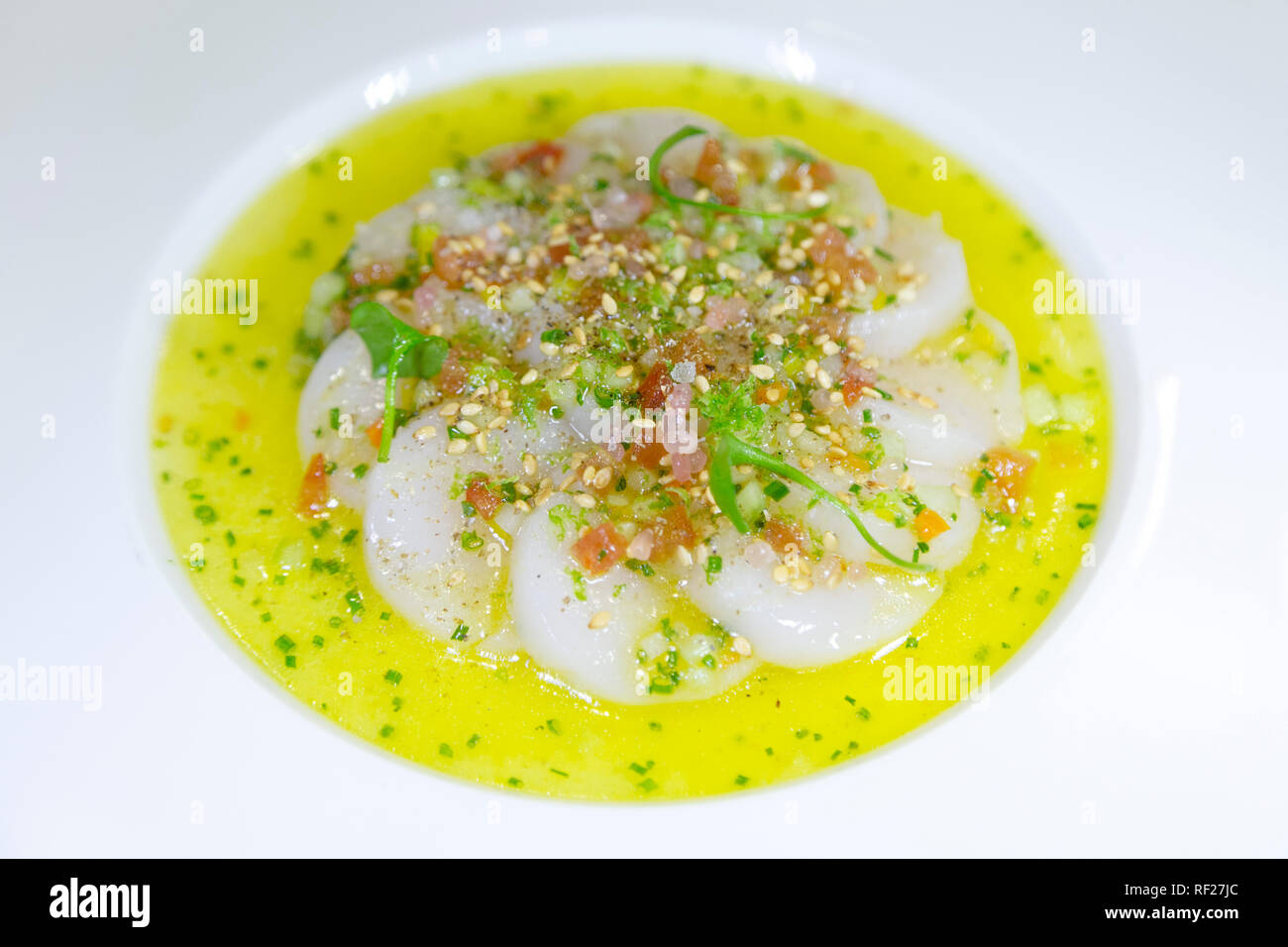 Un carpaccio di capesante servito in una salsa piccante con succo di limone e olio d'oliva. Foto Stock