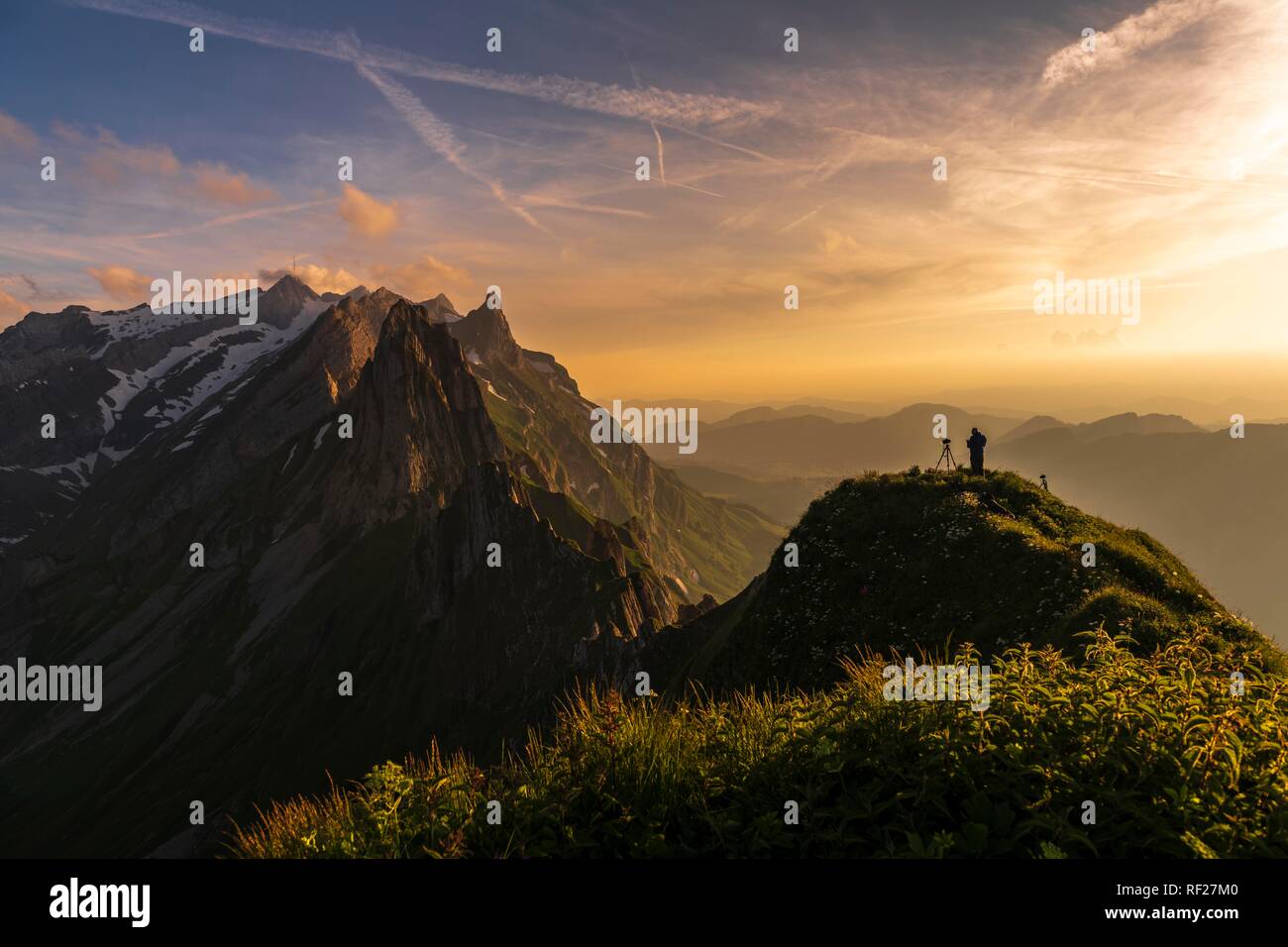 Fotografo sul costone erboso al tramonto con il Säntis picco in background, Wasserauen, Appenzell, Svizzera Foto Stock