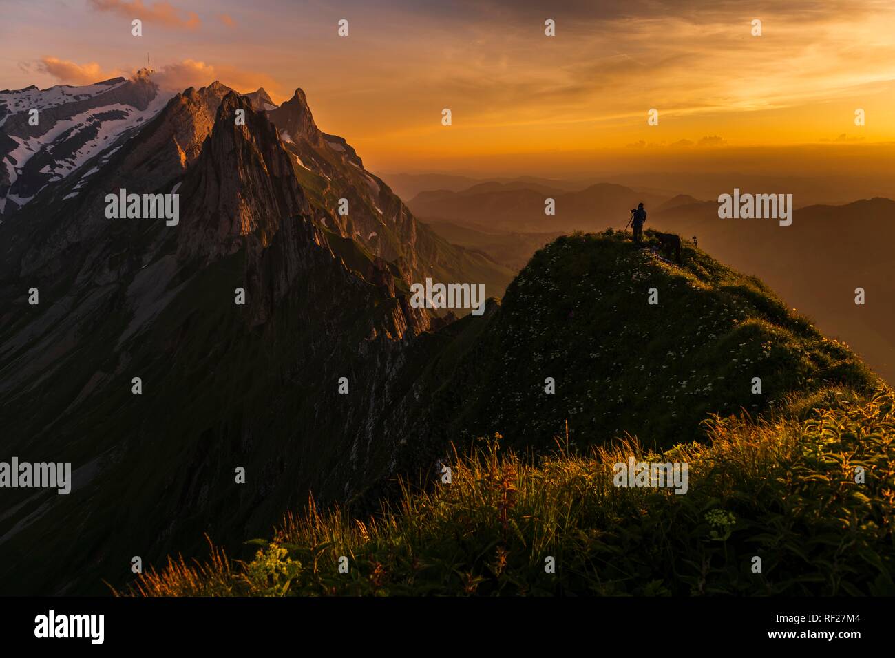 Fotografo sul costone erboso al tramonto con il Säntis picco in background, Wasserauen, Appenzell, Svizzera Foto Stock