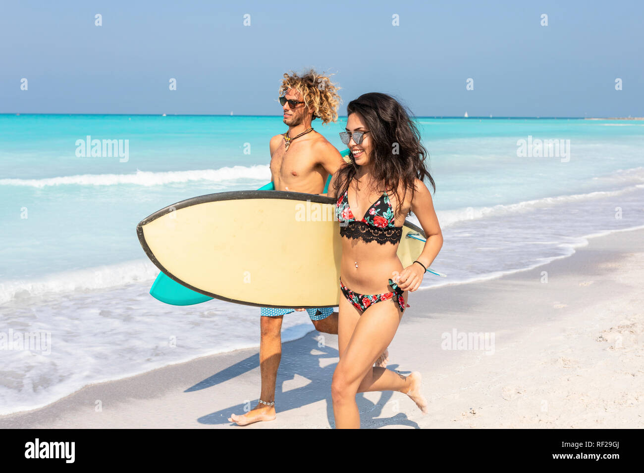 Matura in esecuzione sulla spiaggia, portando le tavole da surf Foto Stock