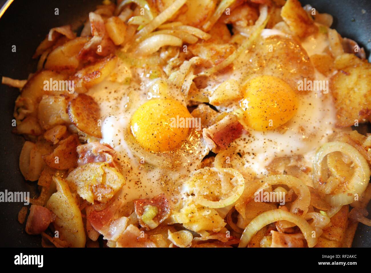 Omelette preparate in una padella, patate fritte, cipolla, pancetta e uova fritte Foto Stock