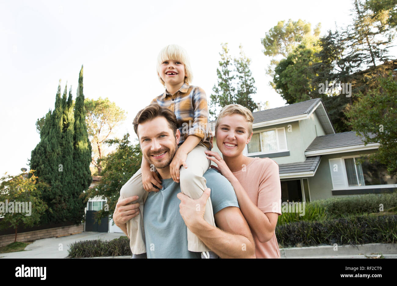 Ritratto di sorridere ai genitori con figlio davanti alla loro casa Foto Stock