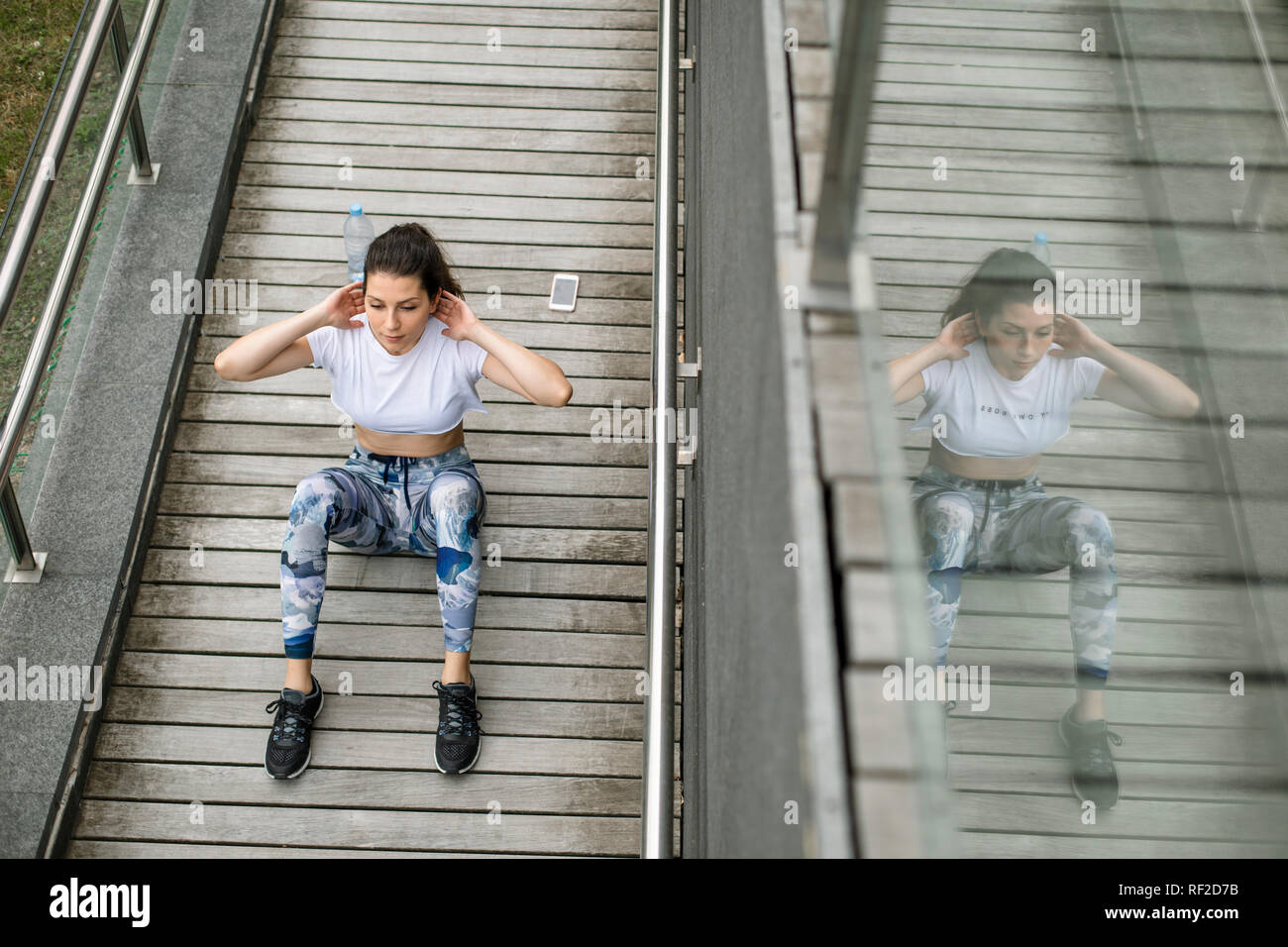 Giovane donna facendo situps su una passerella Foto Stock