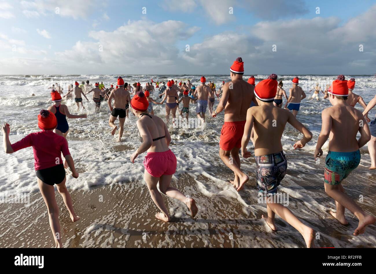 Molte persone in costume da bagno e cappelli di Natale correre nel mare  freddo in inverno, Nuovo Anno di nuoto, Mare del Nord, Bergen aan Zee Foto  stock - Alamy