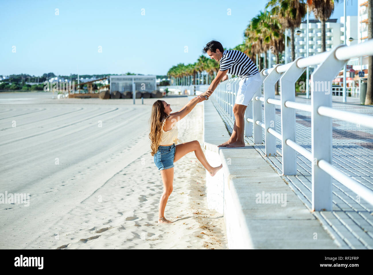 Uomo Donna aiuta a salire dalla spiaggia alla promenade Foto Stock