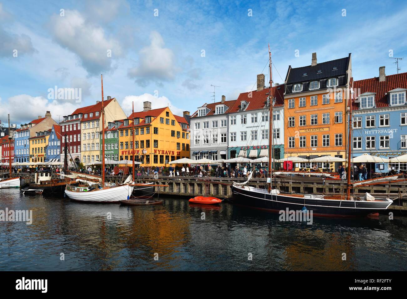 Barche a vela sul canale di fronte a casa colorate facciate, il quartiere del divertimento, Nyhavn, Copenhagen, Danimarca Foto Stock