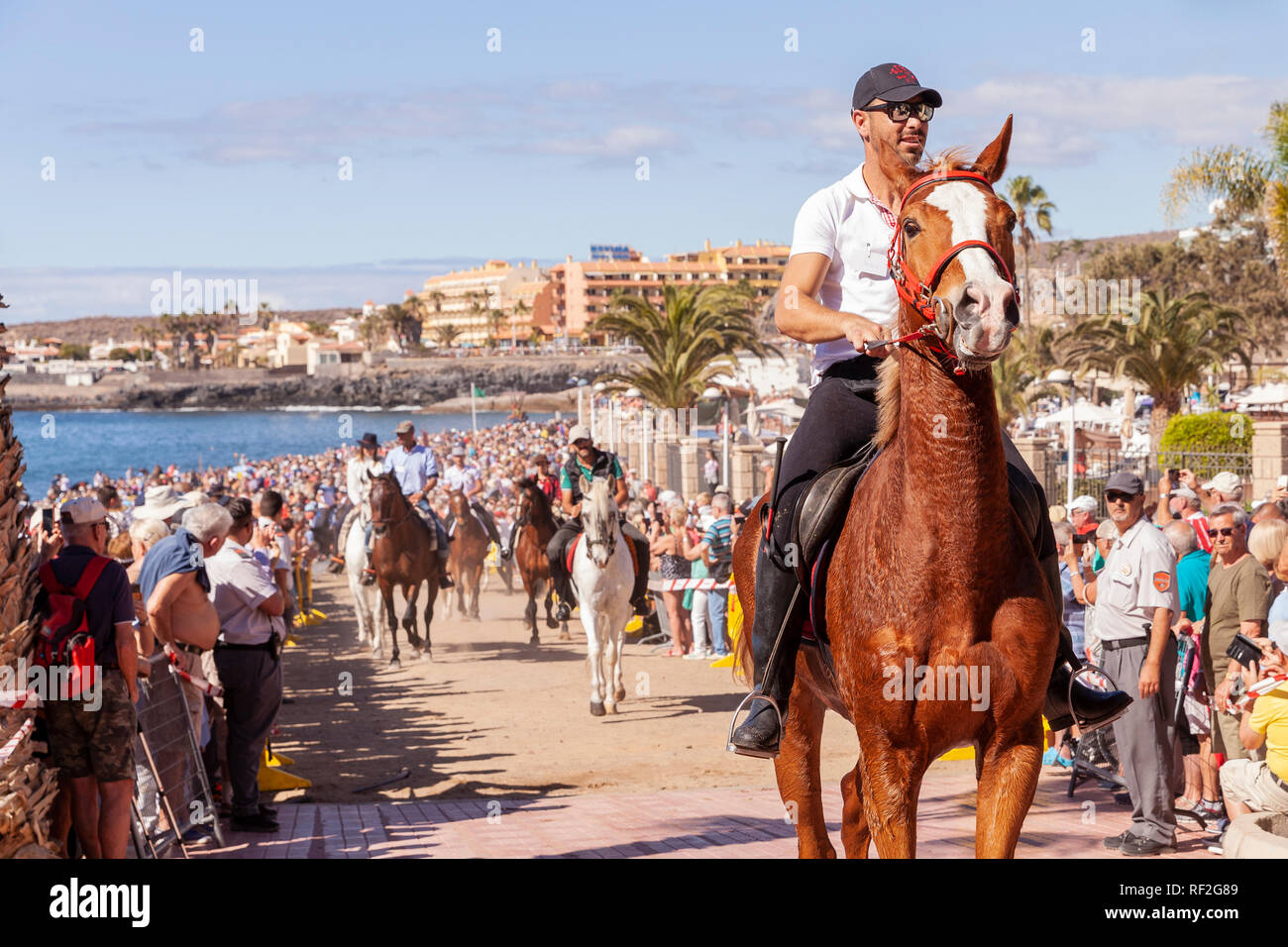 Cavalli e Cavalieri lasciando La Enramada beach dopo la balneazione i loro animali in mare a San Sebastian romeria, fieasta, La Caleta, Tenerife, può Foto Stock