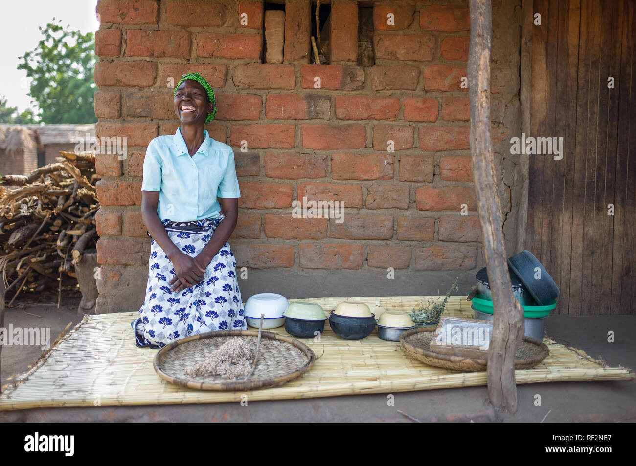 Una donna malawiana sorrisi a dimostrazione di cottura durante una comunità visita per i turisti a Majete riserva faunistica; lei dimostrerà la cottura nsima Foto Stock