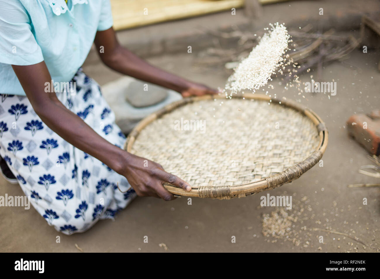 Una donna malawiana dimostra come vagli sorgo durante una comunità visita per i turisti a Majete riserva faunistica; ella mostra come rendere nsima. Foto Stock