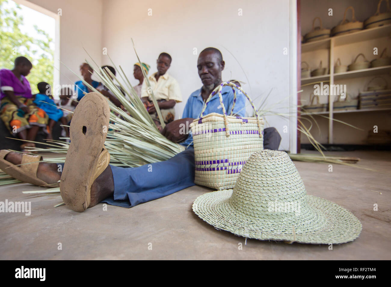 Un uomo del Malawi si intreccia cesti per la comunità di un vasto programma di Majete riserva faunistica, Malawi; Cmmunity membri craft souvenir a vendere Foto Stock