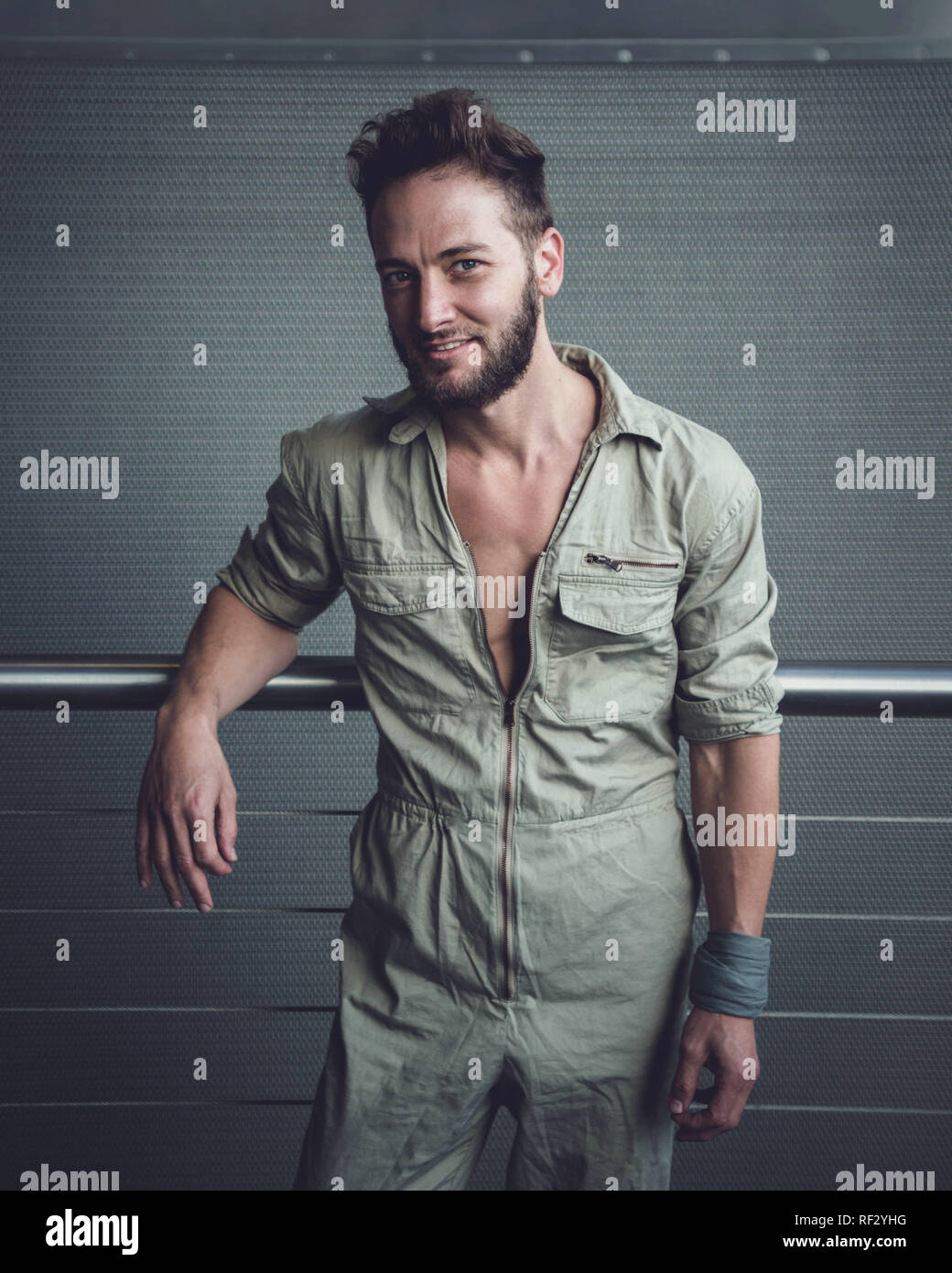 Ritratto di stile di vita di un uomo alla moda in tuta cachi scattato in una moderna posizione industriale. Foto Stock