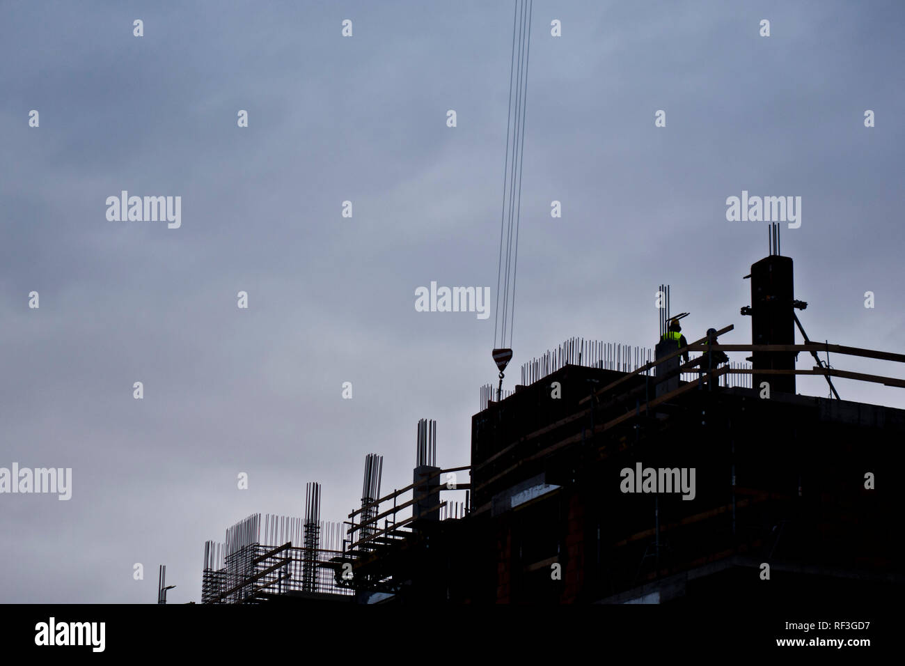 Silhouette dei lavoratori durante la costruzione di un complesso residenziale edificio multipiano Foto Stock