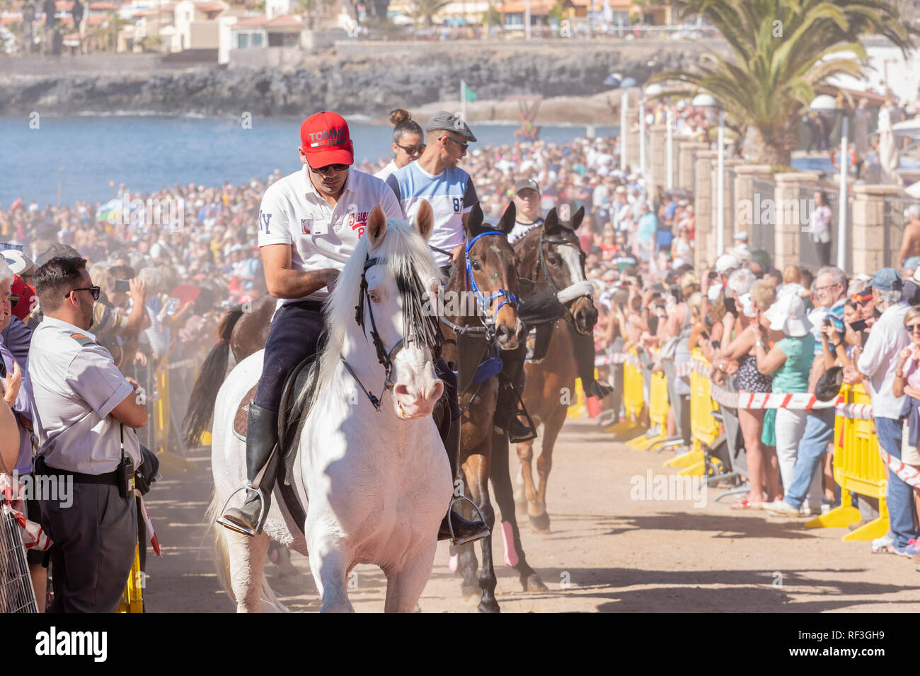 Cavalli e Cavalieri lasciando La Enramada beach dopo la balneazione i loro animali in mare a San Sebastian romeria, fieasta, La Caleta, Tenerife, può Foto Stock