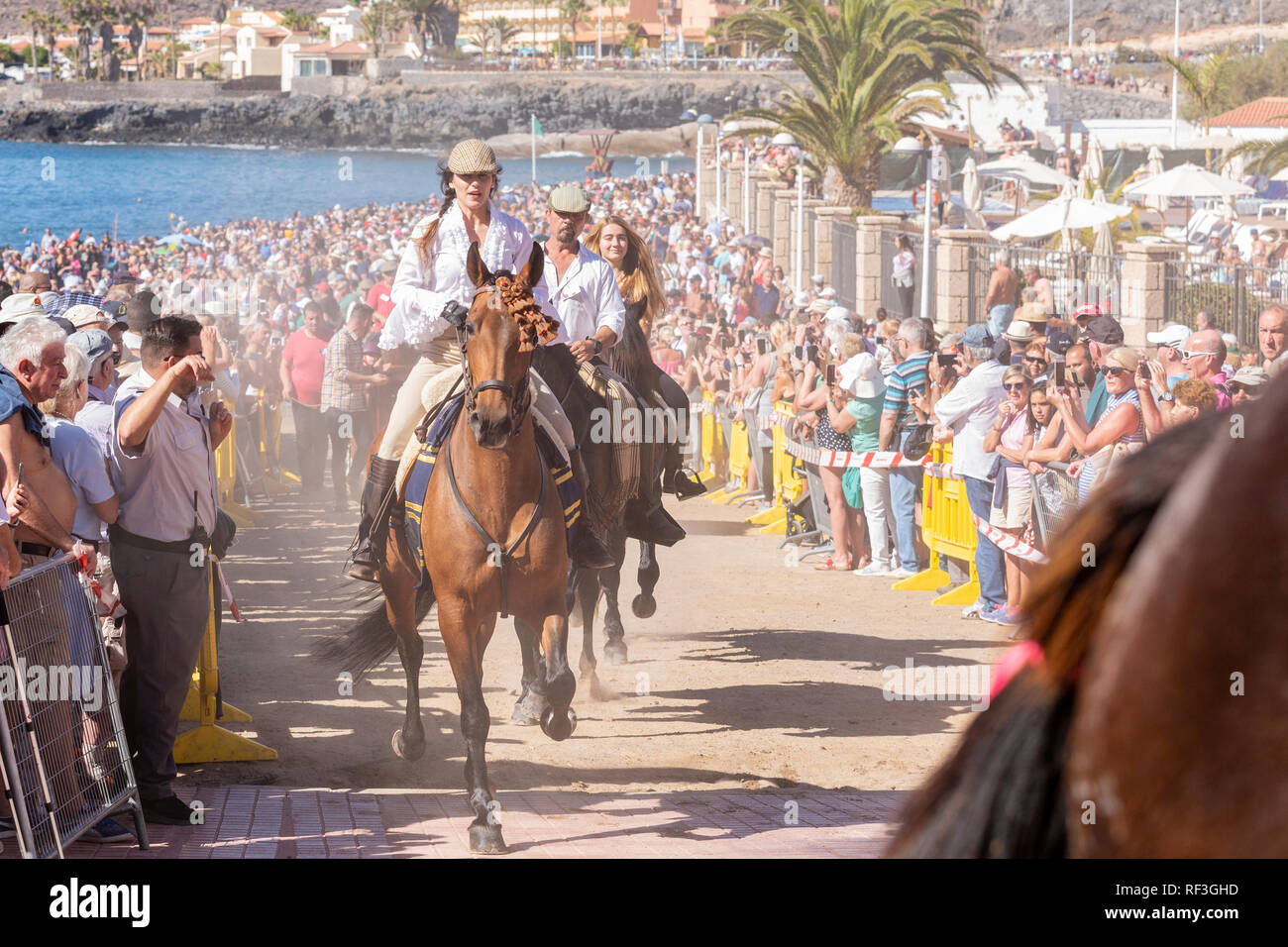 Cavalli e Cavalieri lasciando La Enramada beach dopo la balneazione i loro animali in mare a San Sebastian romeria, fieasta, La Caleta, Tenerife, può Foto Stock