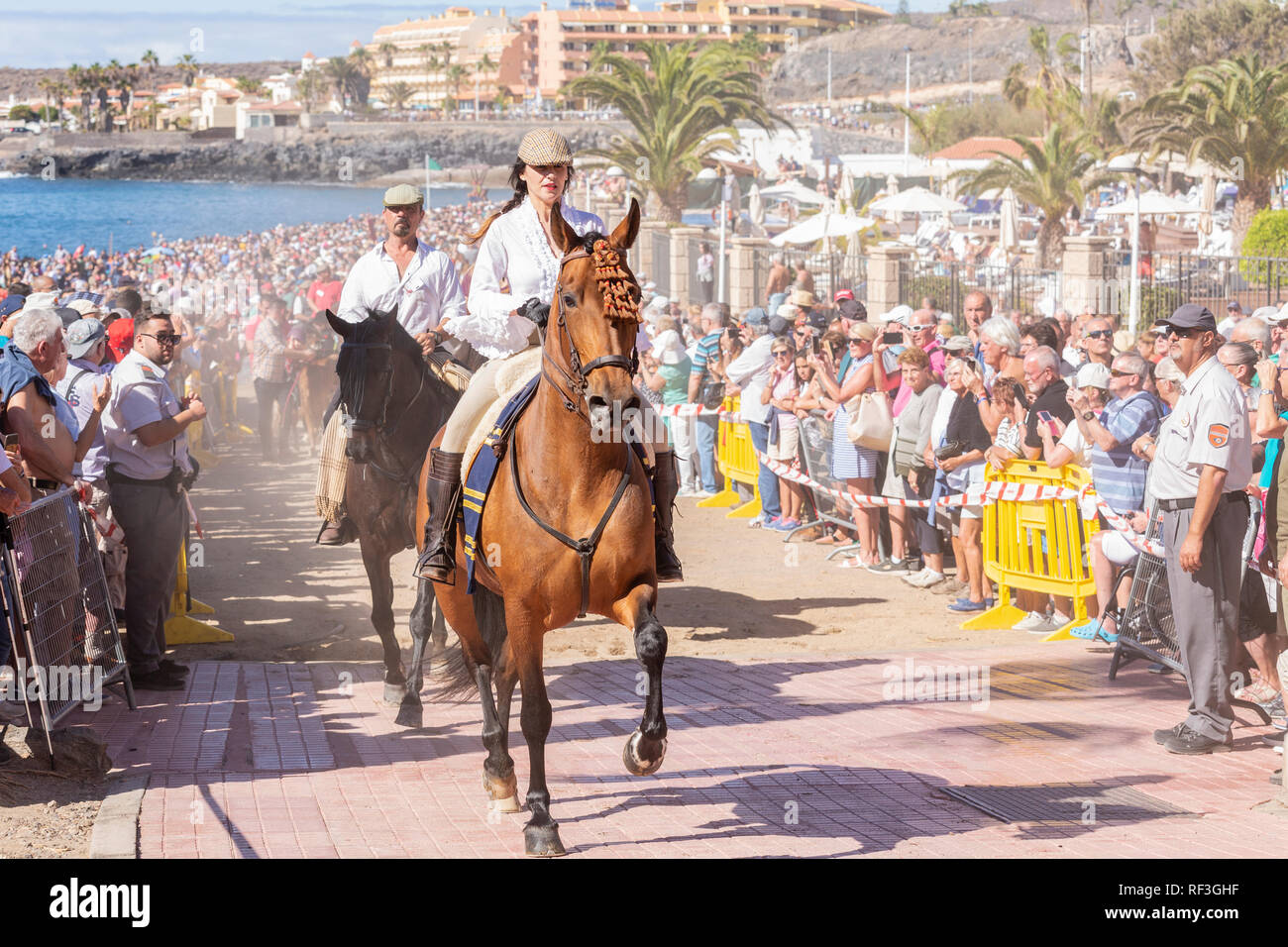 Cavalli e Cavalieri lasciando La Enramada beach dopo la balneazione i loro animali in mare a San Sebastian romeria, fieasta, La Caleta, Tenerife, può Foto Stock