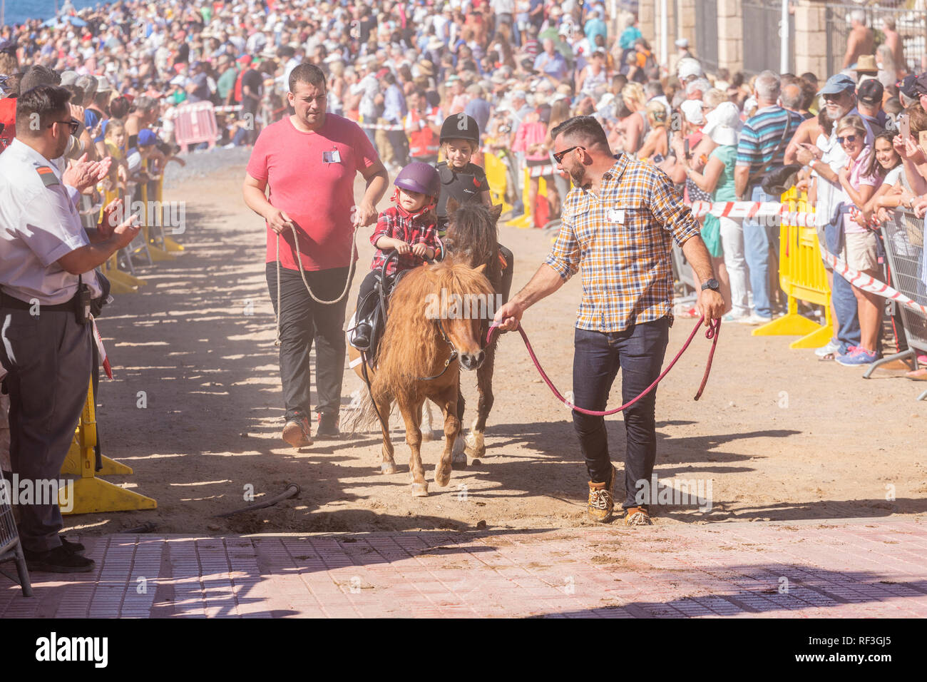 Cavalli e Cavalieri lasciando La Enramada beach dopo la balneazione i loro animali in mare a San Sebastian romeria, fieasta, La Caleta, Tenerife, può Foto Stock