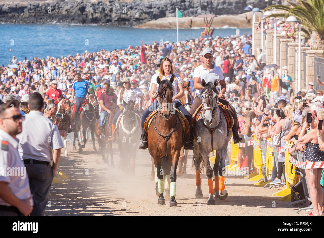 Cavalli e Cavalieri lasciando La Enramada beach dopo la balneazione i loro animali in mare a San Sebastian romeria, fieasta, La Caleta, Tenerife, può Foto Stock