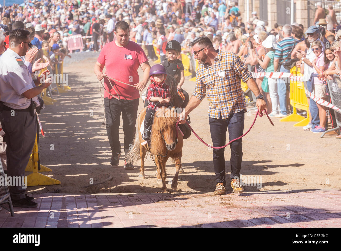 Cavalli e Cavalieri lasciando La Enramada beach dopo la balneazione i loro animali in mare a San Sebastian romeria, fieasta, La Caleta, Tenerife, può Foto Stock